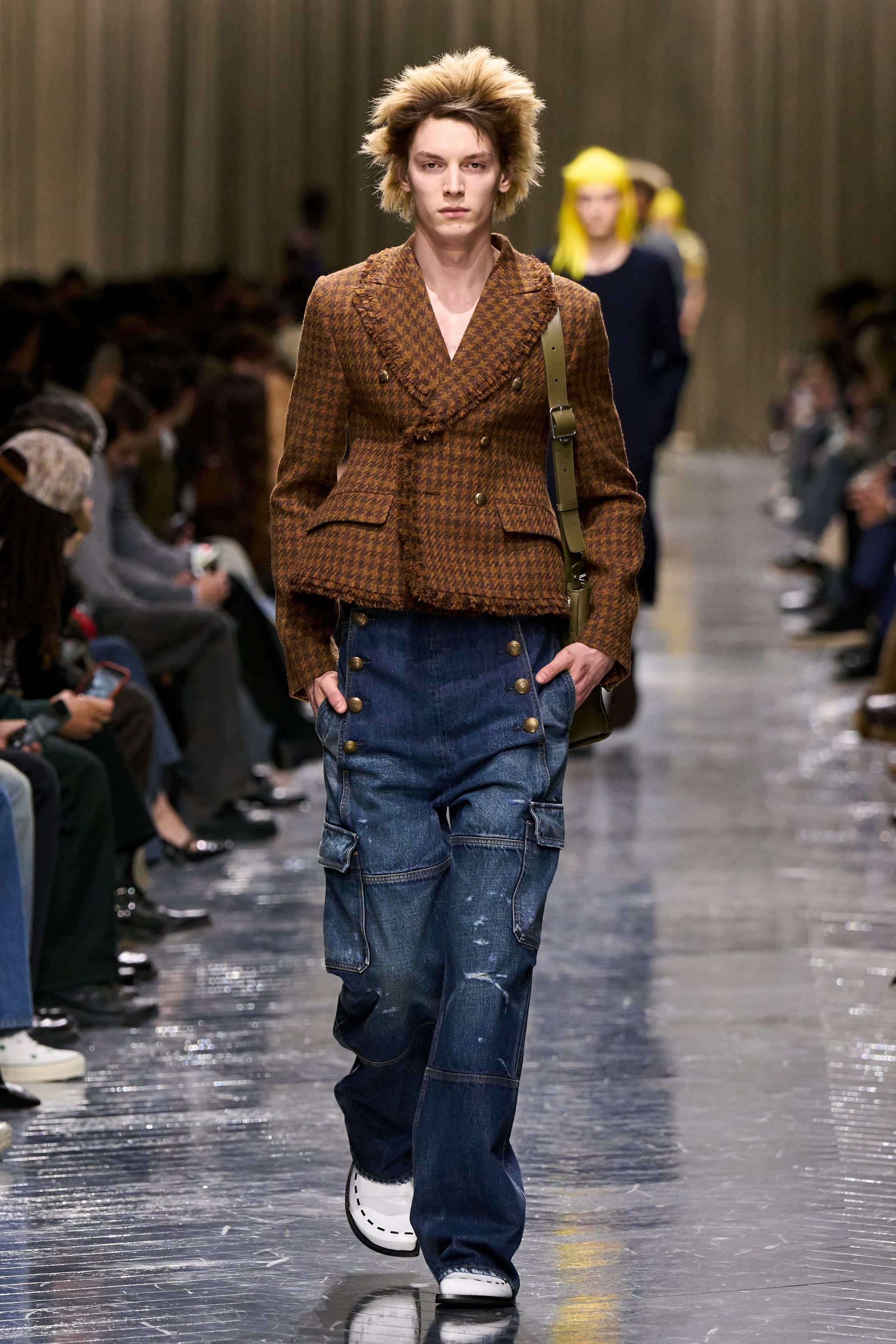 本季 Dior Men 2026 秋冬在克制与叛逆之间建立起新的男性气质坐标。轮廓上，柔软针织、披风式外套与军装结构形成张力对照，模糊正装与休闲、性别与功能的边界；材质层面，羊毛、皮革、毛绒与轻量技术面料并置，强化“触感叙事”。色彩从学院派的灰蓝、橄榄绿过渡至点状印花与手工肌理，传递一种被精心编排的随性。整体呈现出一种“新贵游牧者”形象：既有高级定制的工艺根基，又拥抱当代青年对自由、混搭与身份流动性的渴望-顽石频道趋势研究